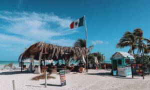 Mexiko Reisetipps und Infos Titelbild - Ein kleine Strandhütte mit Palmen an einem Strand in Holbox